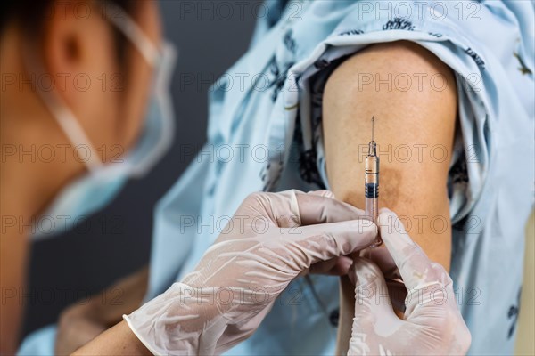 close up doctor in gloves holding syringe and making injection to patient in medical mask. Covid-19 or coronavirus vaccine