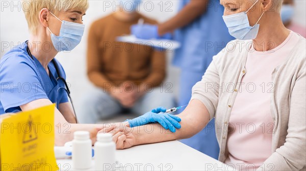 Doctor Giving Older Woman Corona Virus Vaccine Injection In Hospital