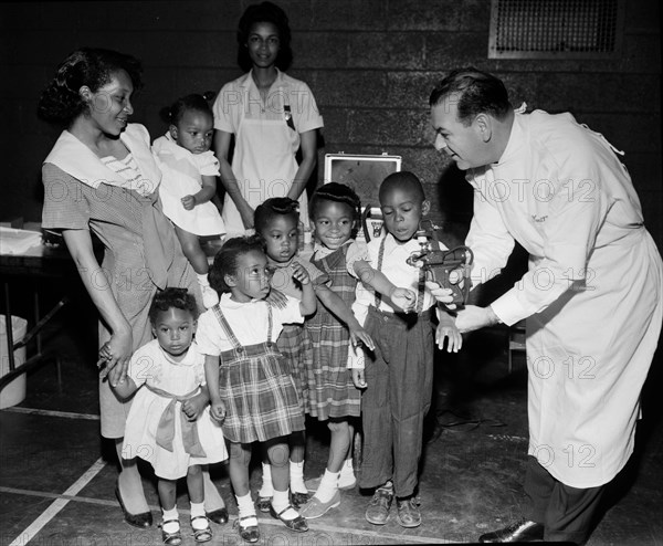 Doctor with a newly-developed jet injector gun prepares to inoculate children on Chicago’s South Side, ca. 1960.