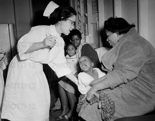 A nurse attempts to give a young child a flu shot in Chicago, ca.1962.