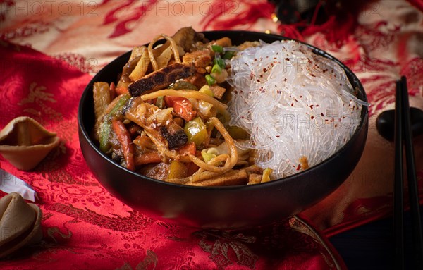 Traditional Chinese Buddha's Delight stir fry for New Year  served in black bowl on traditional red fabric cover