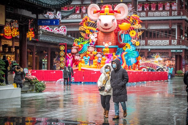 Shanghai, China, 25th Jan 2020, A woman and man in masks walks with Chinese New Year celebration reminders around them