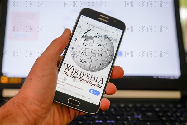 Bordeaux , Aquitaine / France - 10 11 2019 : Hands holding smartphone displaying logo of Wikipedia website homepage on a screen