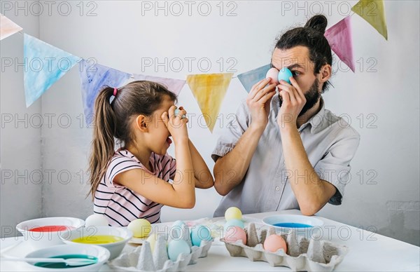 Happy family preparing to Easter celebrate at home. Adorable little girl and her having fun while while dyed easter eggs.