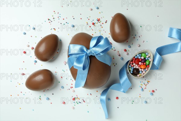 Easter chocolate eggs, candies and sprinkles on white background