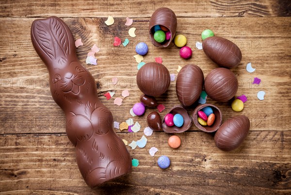 Delicious chocolate easter eggs and sweets on wooden background