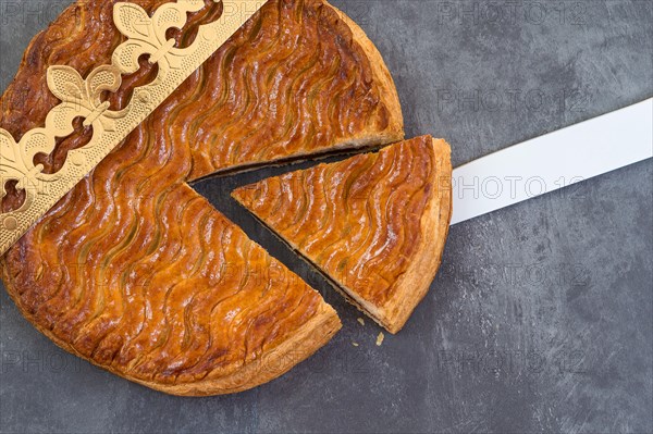 Galette des rois, french kingcake with a golden crown on a grey slate background