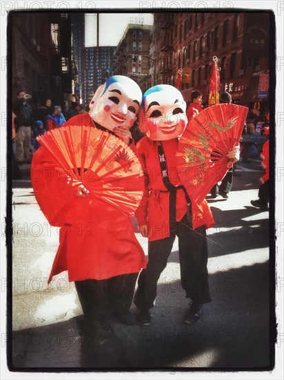 Two people with ceremonial masks and fans at Chinese new year celebration in New York City