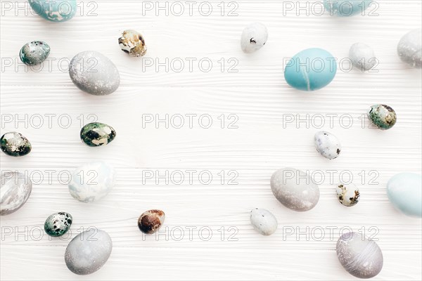 Happy Easter, greeting card mockup. Stylish Easter eggs frame, flat lay on white wooden background with space for text. Modern easter eggs painted wit