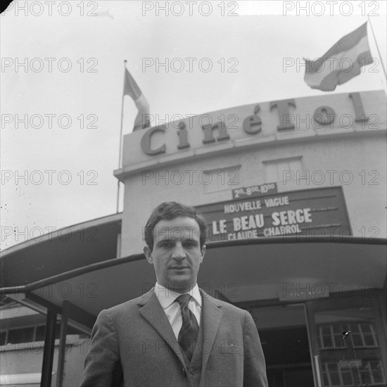 French director Francois Truffaut for cinema Cinétol, where his film plays [Le Peau Douce?] during Nouvelle Vague festival [on billboard film by Claude Chabrol Le Beau Serge] Date: 15 March 1965 Location: Amsterdam, Noord-Holland Keywords: cinemas, films, portraits, directors Personal name: Cinetol, Truffaut, François