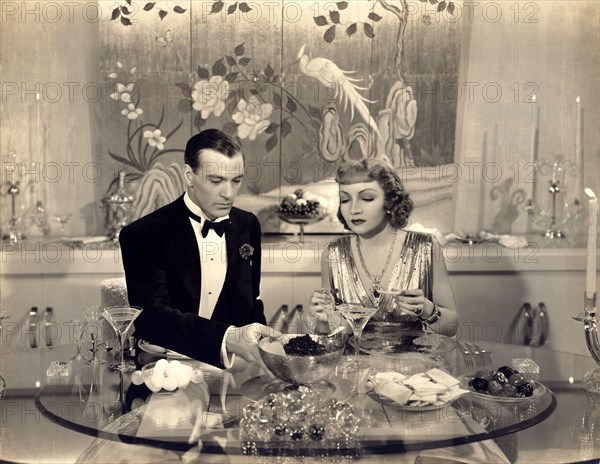 1938 , USA : The movie actors GARY COOPER and CLAUDETTE COLBERT in " Bluebeard's Eight Wife " ( 1938 - L' ottava moglie di Barbablu' ) by Ernst Lubitsch - MOVIE - FILM - CINEMA - marito e moglie - matrimonio - bionda - capelli biondi - blonde hair - amanti - lovers -  husband - wife - marriage - CIBO - FOOD - DIETA - DIET - frutta candita - fruits - attori che mangiano - mangiare - eating - ATTORE CINEMATOGRAFICO  - sex symbol -  DIVO - FILM  - LOVERS - INNAMORATI - AMANTI -  tavola - cucina - cena - dinner - caviar - caviale - silver golden dress - abito dorato argentato - lame' - FASHION - M