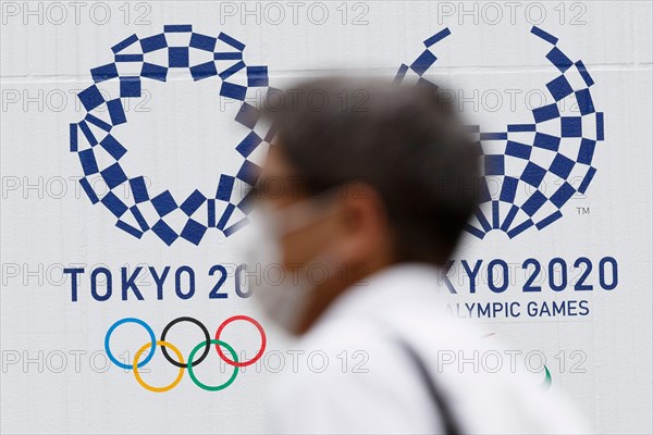 Tokyo, Japan. 18th June, 2020. A man wearing a face mask walks past the logos of Tokyo 2020 Olympic and Paralympic Games in downtown Tokyo. Japanese media reported that an executive board member of Tokyo 2020 said to seek another delay should be an option if the games can not be held next year due to the coronavirus pandemic. The International Olympic Committee and the local organizing committee have said the games will be canceled if they can not be held next July 2021. Credit: Rodrigo Reyes Marin/ZUMA Wire/Alamy Live News