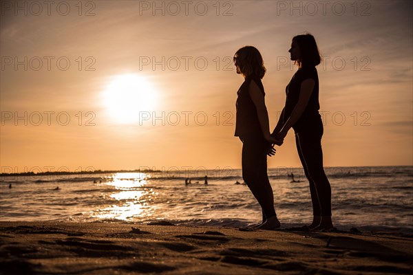 A couple of lesbian girls in an orange sunset on the beach
