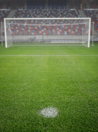 Shallow depth of field (selective focus) image with the penalty kick point on an empty soccer stadium.