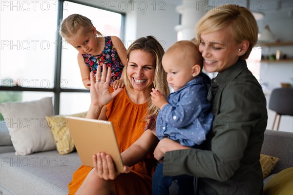 Happy lesbian couple playing, spending time with children at home