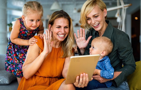 Happy lesbian couple playing, spending time with children at home