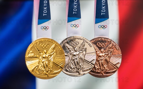 April 25, 2021 Tokyo, Japan. Gold, silver and bronze medals of the XXXII Summer Olympic Games 2020 in Tokyo on the background of the flag of France.