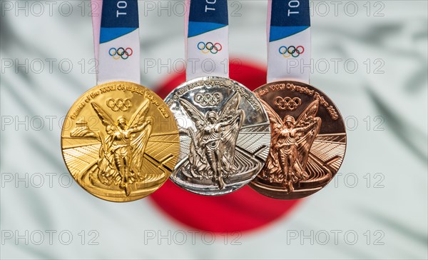 April 25, 2021 Tokyo, Japan. Gold, silver and bronze medals of the XXXII Summer Olympic Games 2020 in Tokyo on the background of the flag of Japan.