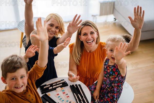 Lesbian couple at the table playing board game with children.