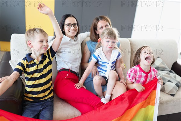 Lgbt family two women with joyful children hold flag
