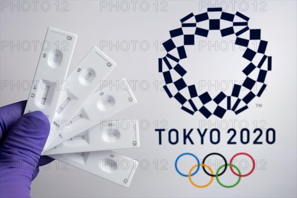 Negative PCR tests in front and blurred Tokyo 2020 logo on the blurred background. Concept for Tokyo COVID Olympic games in 2021. Stafford, United Kin