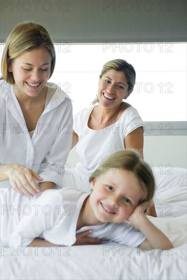 Girl relaxing on bed with her mother and grandmother
