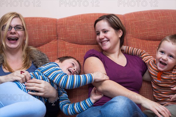 Two happy women playing with children at home