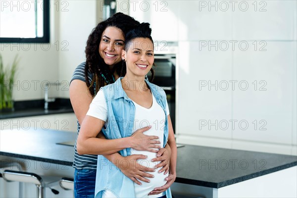 Portrait of pregnant lesbian couple embracing