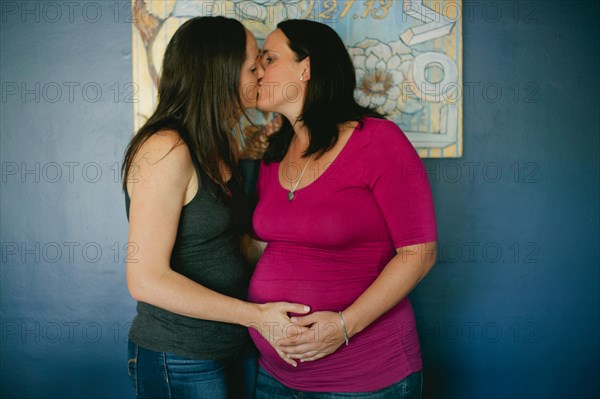 Homosexual couple kissing while standing against wall at home