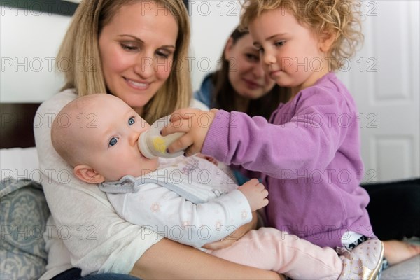 Caucasian girl feeding bottle to baby sister