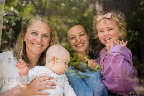 Caucasian mothers and daughters waving behind window