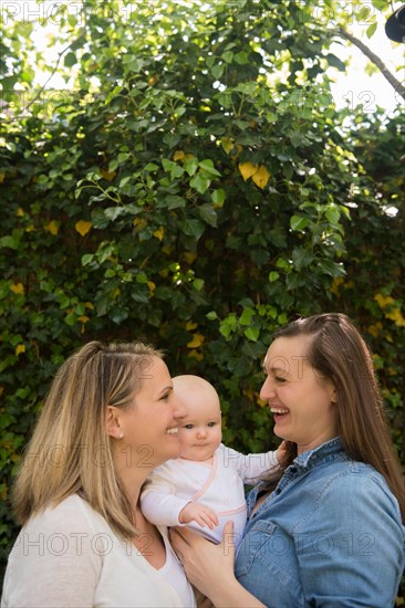 Caucasian mothers hugging baby daughter near tree