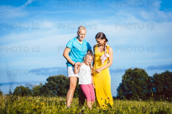 Two women with child on a meadow