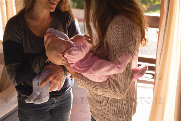 Lesbian couple holding their babies at home