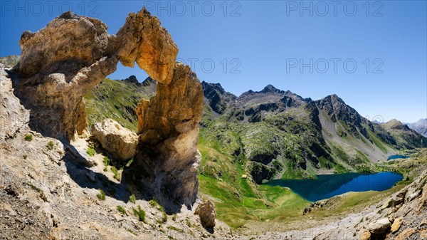 The Arc de Tortisse, famous natural limestone arch in the national park of Mercantour (France) with the upper lake of Vens on the background