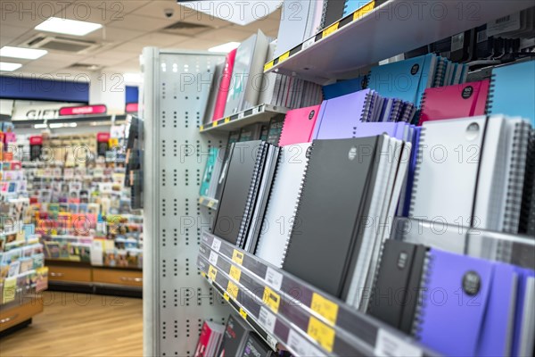 Colourful selection of various sizes and styles of notebooks and other stationary products seen on the lower shelves of a well-known bookstore.