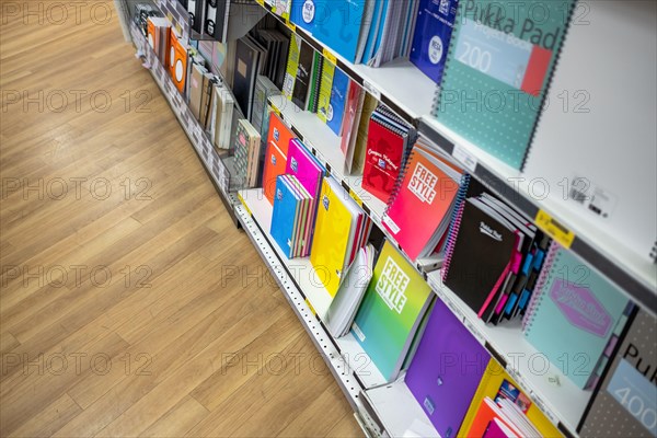 Colourful selection of various sizes and styles of notebooks and other stationary products seen on the lower shelves of a well-known bookstore.