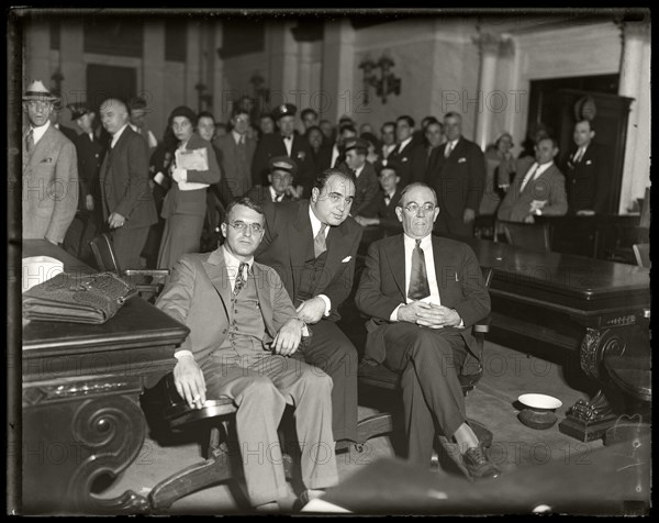 Al Capone sits in federal court during his tax evasion trial with his attorneys Michael Ahern, left, and Albert Fink, right. Chicago, Illinois,  October 7, 1931. Image from 4x5 inch glass negative.