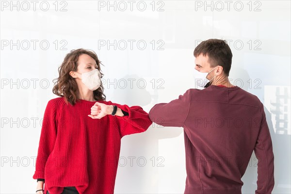 Two people greet elbow bump. Greeting with elbow bump in street. Colleagues are doing elbow bumps in office. New style of greeting during coronavirus.