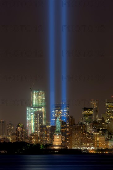 The twin beams of light of the Tribute in Light, an annual remembrance to the events of September 11, 2001, shine into the night sky in New York City on either side of the Statue of Liberty.