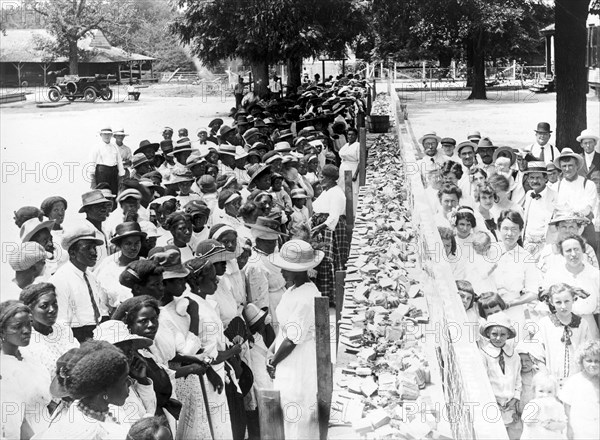 Entitled: "F.M. Gay's annual barbecue given on his plantation every year" shows crowds of African-American and white people separated by a long counter covered with slices of bread at a barbecue in Alabama. Segregation is separation of humans into racial