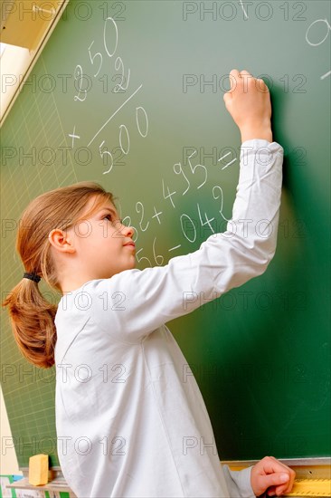 School girl writing on blackboard