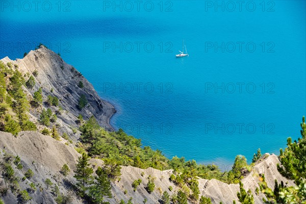 Serre-Poncon Lake in summer with deep blue water and sailing boat. Hautes-Alpes, PACA Region, Southern French Alps, France
