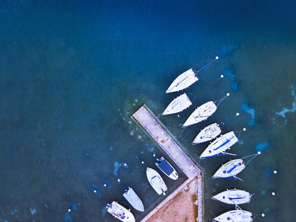 aerial view of boats parked near pier on the lake, blue water landscape from drone
