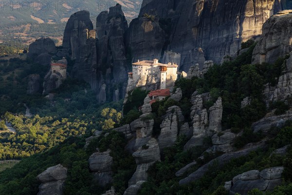 Rousanou and St. Nikolaos Anapafsas Monasteries (Meteora, Greece) during sunrise with dark colored cliffs on the back ground