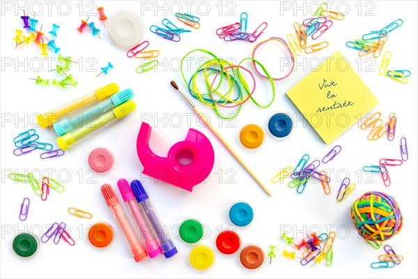 Vive la rentree (meaning back to school in French) written on sticky notes among  colorful school supplies  isolated on white background.