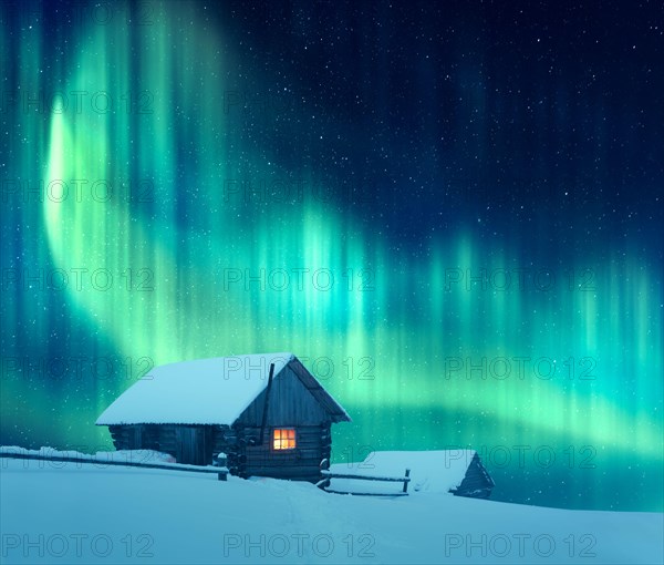 Fantastic winter landscape with wooden house with light in window in snowy mountains and northen light in night sky. Christmas holiday and winter vacations concept