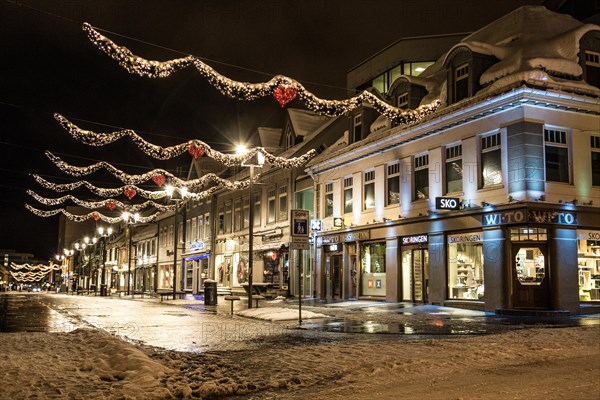 A view of the central street of Tromsø, Storgata, at polar night in winter, all lit up, with decorations for Christmas.