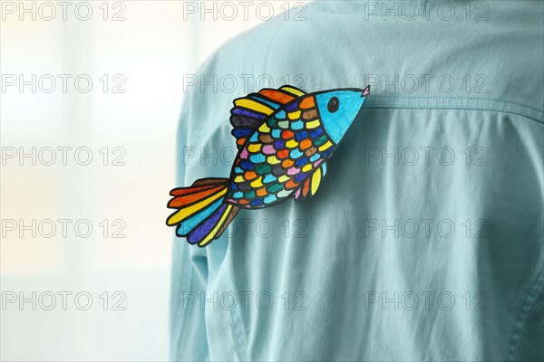 Paper fish on man's back, closeup. April fool's day prank