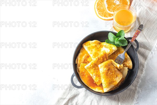 Crepes with Orange Sauce in a cast iron pan. Traditional French crepe Suzette with orange sauce.